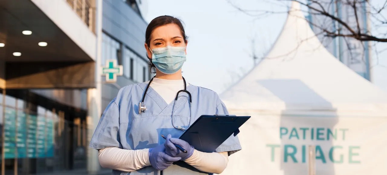 Triage nurse standing in front of a tent for checking patients